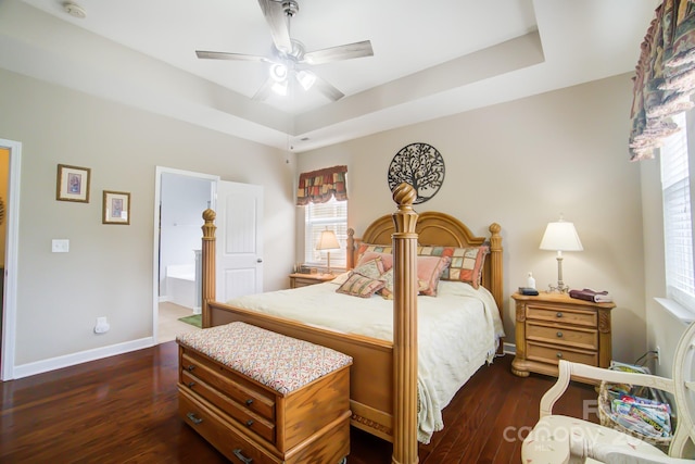 bedroom featuring a ceiling fan, wood finished floors, ensuite bathroom, a raised ceiling, and baseboards