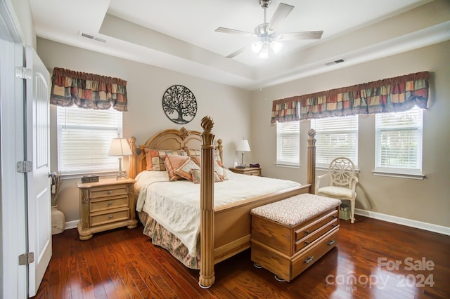 bedroom featuring visible vents, baseboards, a tray ceiling, and dark wood finished floors