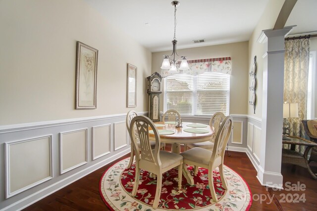dining area featuring a decorative wall, wainscoting, dark wood finished floors, a notable chandelier, and visible vents