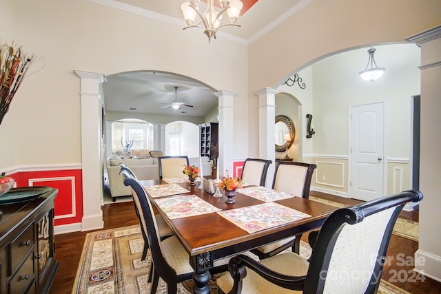 dining space with decorative columns, a ceiling fan, arched walkways, dark wood-type flooring, and wainscoting
