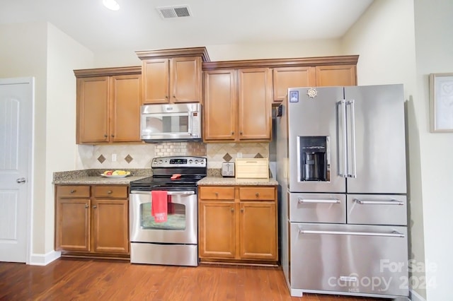kitchen with dark wood finished floors, tasteful backsplash, visible vents, and appliances with stainless steel finishes