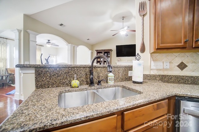 kitchen with vaulted ceiling, hardwood / wood-style flooring, light stone countertops, and sink