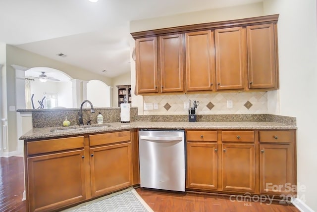 kitchen featuring light stone countertops, hardwood / wood-style flooring, dishwasher, sink, and backsplash