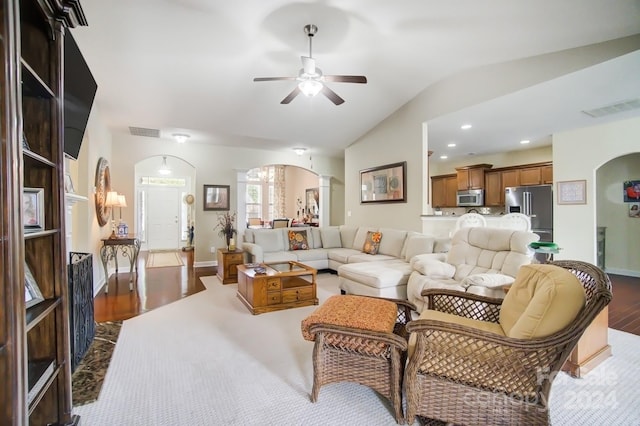 living room featuring arched walkways, dark wood-style flooring, visible vents, and ornate columns