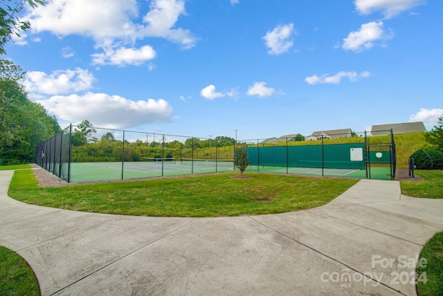 view of tennis court with a gate, a yard, and fence