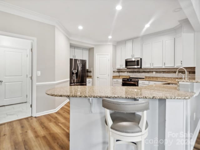 kitchen with light wood-type flooring, sink, white cabinets, stainless steel appliances, and light stone countertops