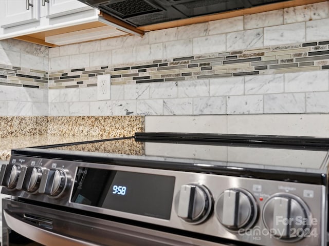 details with white cabinetry, tasteful backsplash, and stainless steel range oven