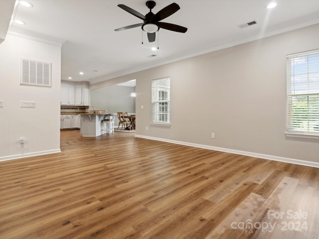 unfurnished living room featuring ceiling fan, light hardwood / wood-style flooring, and ornamental molding