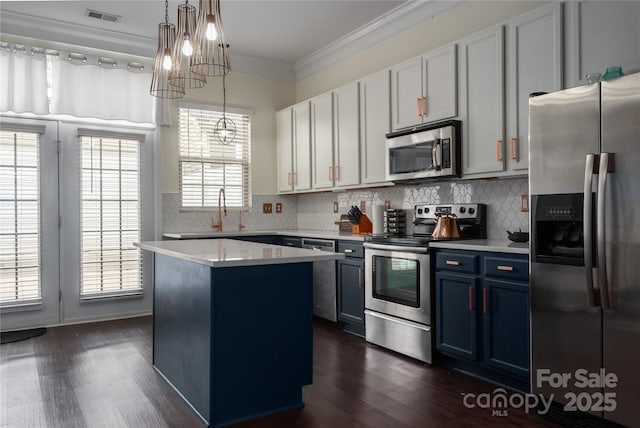 kitchen featuring blue cabinetry, hanging light fixtures, stainless steel appliances, a center island, and ornamental molding