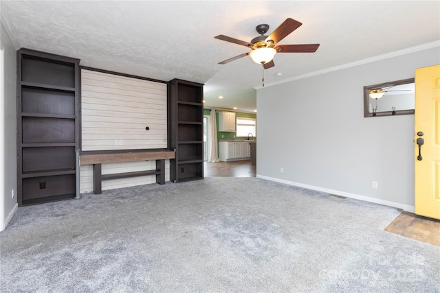 unfurnished living room with sink, a textured ceiling, ornamental molding, carpet floors, and ceiling fan