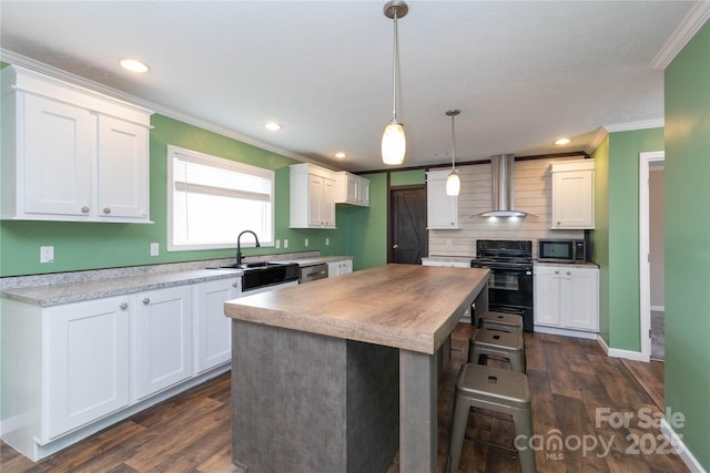 kitchen with pendant lighting, sink, white cabinets, range, and wall chimney exhaust hood