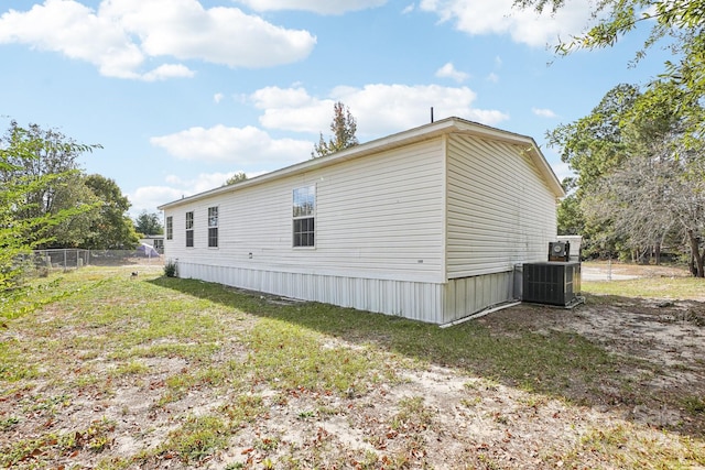 view of property exterior with central AC unit and a lawn