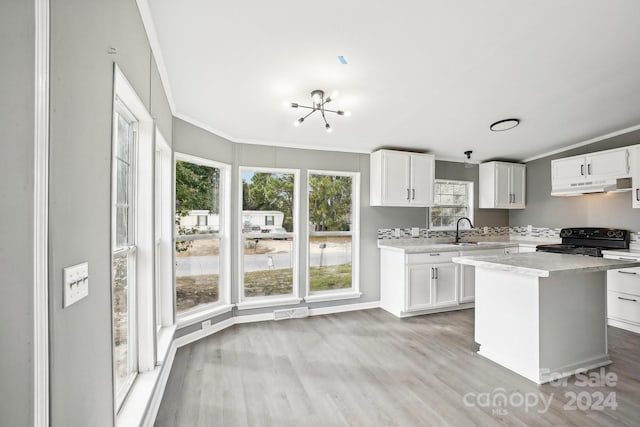 kitchen featuring white cabinetry, light wood-type flooring, black stove, and a kitchen island