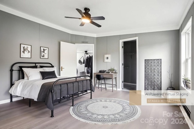 bedroom with hardwood / wood-style flooring, ceiling fan, a closet, a spacious closet, and multiple windows