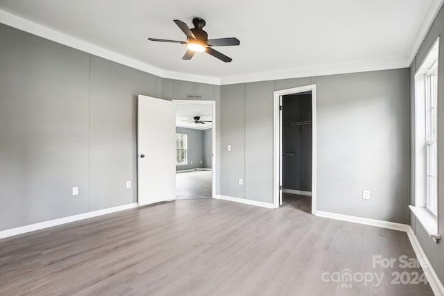 unfurnished bedroom featuring ceiling fan, multiple windows, and a spacious closet