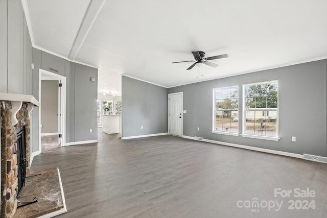 unfurnished living room featuring a stone fireplace, dark wood-type flooring, ceiling fan, and crown molding