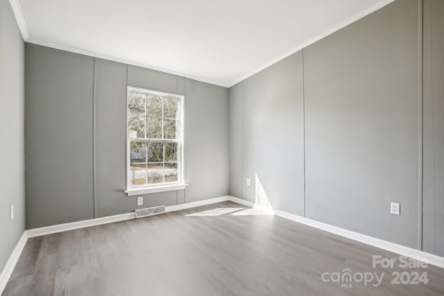 empty room featuring a wealth of natural light, hardwood / wood-style floors, and crown molding