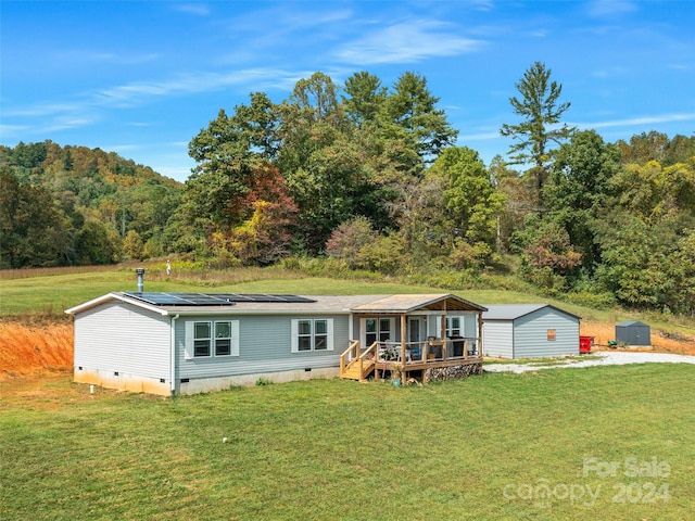 manufactured / mobile home featuring an outbuilding, a wooden deck, and a front yard