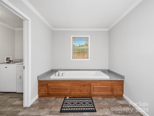 bathroom featuring crown molding, washer and dryer, and a bathing tub