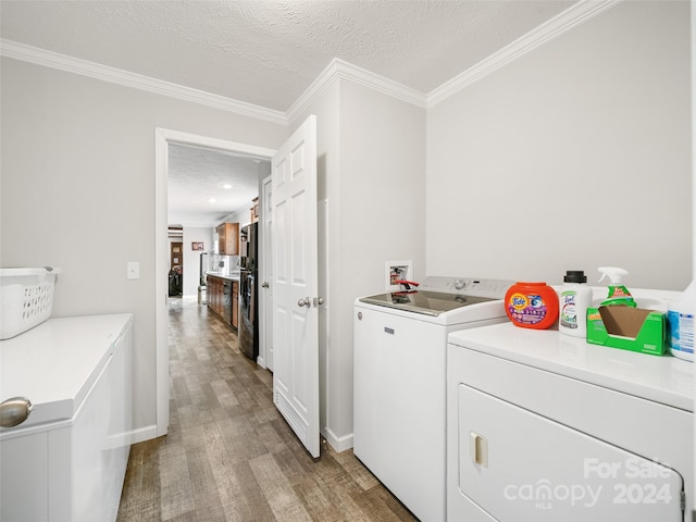 washroom with a textured ceiling, hardwood / wood-style floors, independent washer and dryer, and crown molding