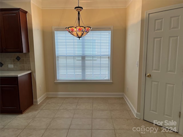 unfurnished dining area with light tile patterned flooring, ornamental molding, and a wealth of natural light