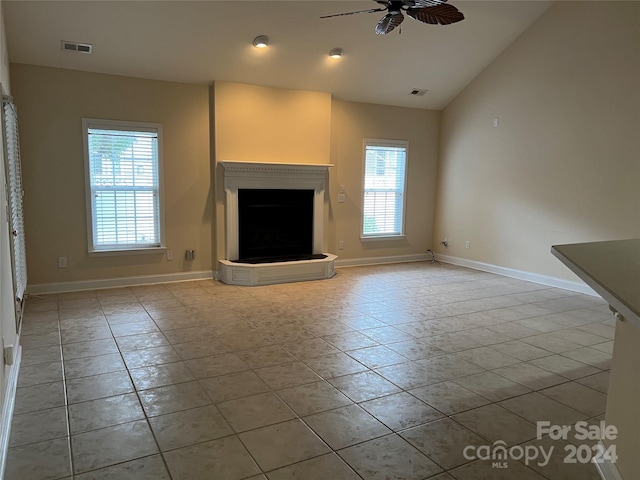 unfurnished living room featuring a wealth of natural light, vaulted ceiling, and light tile patterned floors