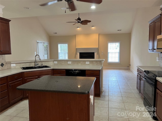 kitchen featuring light tile patterned floors, sink, a kitchen island, black appliances, and vaulted ceiling