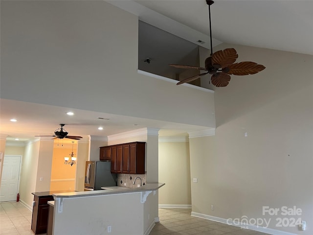 kitchen with stainless steel refrigerator, kitchen peninsula, backsplash, ceiling fan with notable chandelier, and crown molding