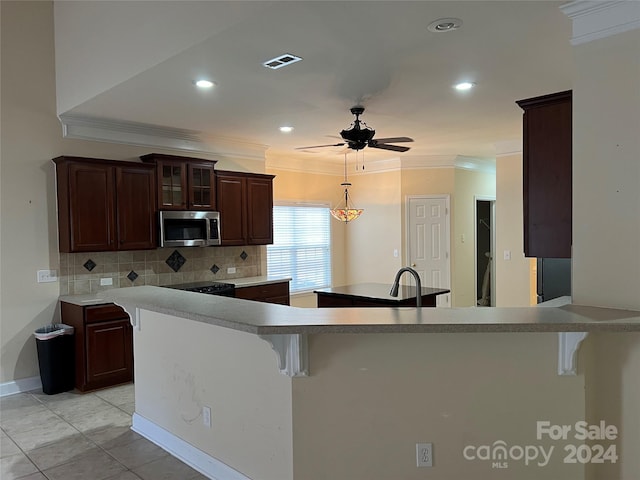 kitchen with a breakfast bar, backsplash, kitchen peninsula, and crown molding