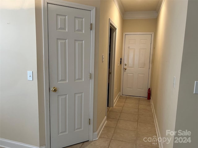 corridor with crown molding and light tile patterned floors