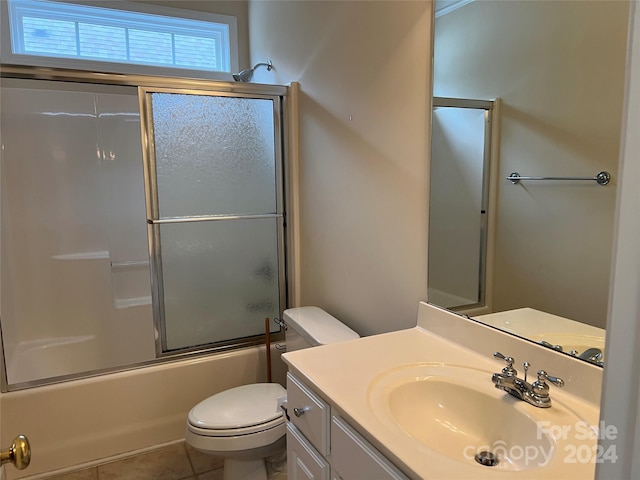 full bathroom with tile patterned flooring, shower / bath combination with glass door, toilet, and vanity