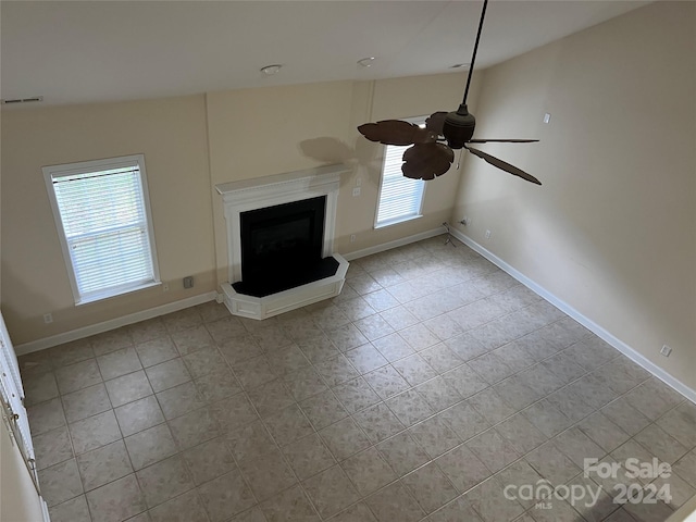 unfurnished living room featuring light tile patterned floors, vaulted ceiling, ceiling fan, and plenty of natural light