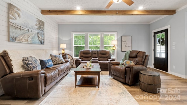 living room featuring ceiling fan, a textured ceiling, light wood-type flooring, and beam ceiling