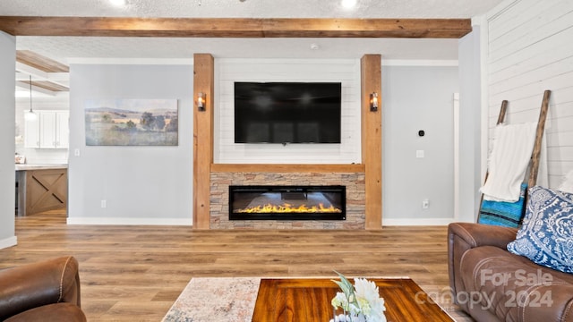 living room featuring a textured ceiling, a fireplace, hardwood / wood-style floors, and beamed ceiling