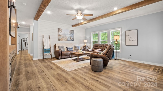 living room featuring light wood-type flooring, a textured ceiling, beamed ceiling, and ceiling fan