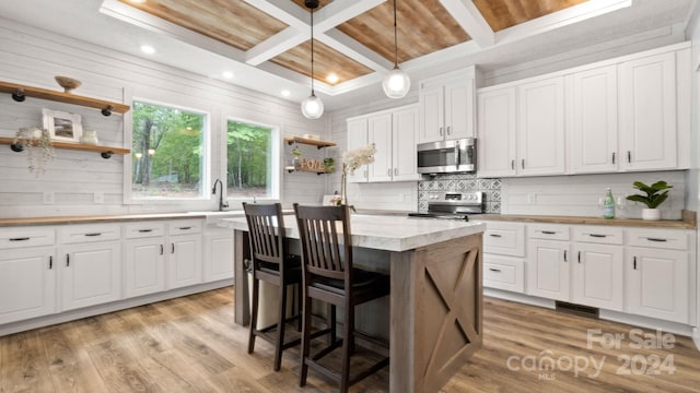 kitchen with light hardwood / wood-style flooring, white cabinetry, appliances with stainless steel finishes, and a center island