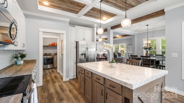 kitchen with appliances with stainless steel finishes, hanging light fixtures, white cabinetry, dark wood-type flooring, and a kitchen island