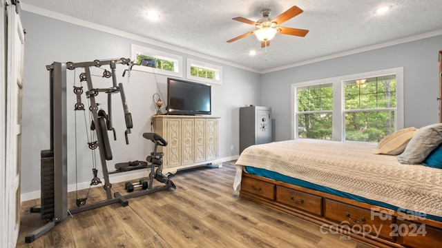 bedroom featuring a textured ceiling, crown molding, hardwood / wood-style floors, and ceiling fan