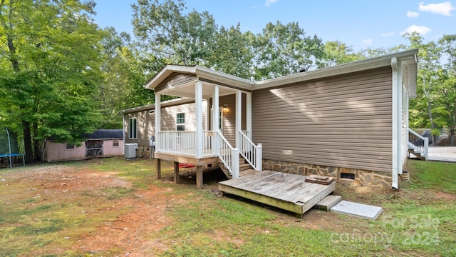 rear view of property featuring a storage shed and central AC