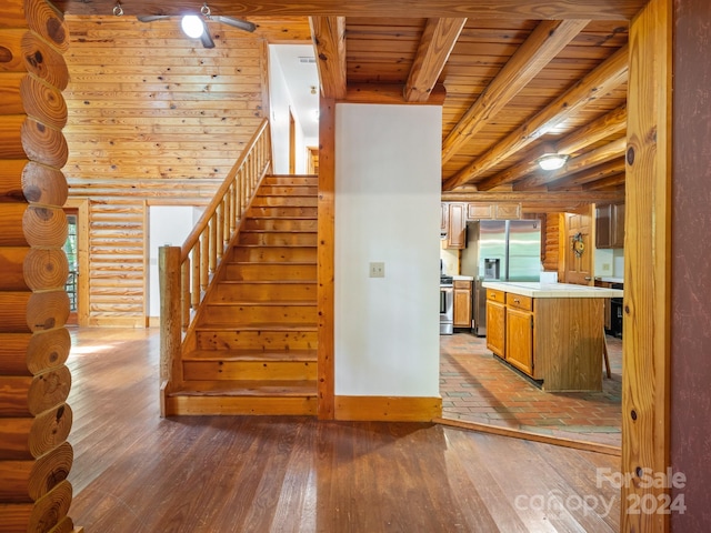 interior space featuring wooden ceiling, wood-type flooring, beam ceiling, ceiling fan, and rustic walls