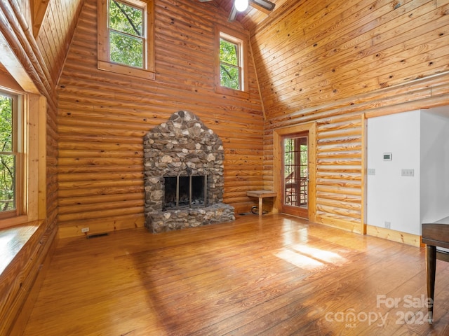 unfurnished living room featuring ceiling fan, wood ceiling, a stone fireplace, high vaulted ceiling, and hardwood / wood-style flooring