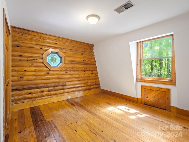 spare room with rustic walls and hardwood / wood-style floors