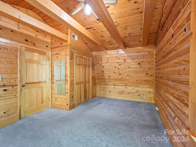 interior space with wood ceiling, wood walls, beamed ceiling, ceiling fan, and carpet