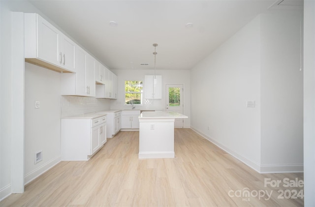 kitchen featuring light hardwood / wood-style floors, white cabinetry, tasteful backsplash, hanging light fixtures, and a kitchen island