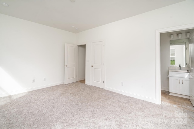 unfurnished bedroom featuring light carpet, sink, and connected bathroom