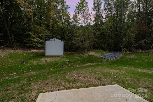 yard at dusk featuring a storage shed