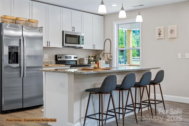 376 Hague Dr, Columbus, NC 28722 - kitchen featuring appliances with stainless steel finishes, wood finished floors, white cabinetry, a center island with sink, and recessed lighting
