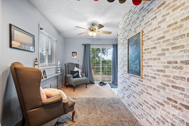 living area featuring ceiling fan, a textured ceiling, brick wall, and carpet