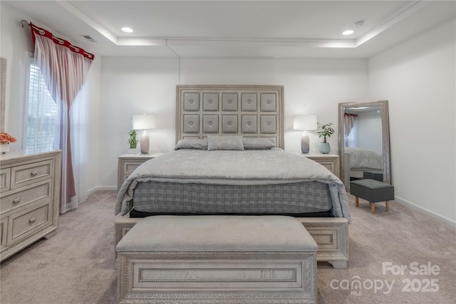 bedroom with light colored carpet and a tray ceiling