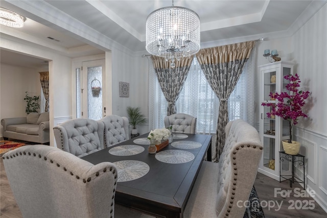 dining space with ornamental molding, a tray ceiling, a chandelier, and hardwood / wood-style floors